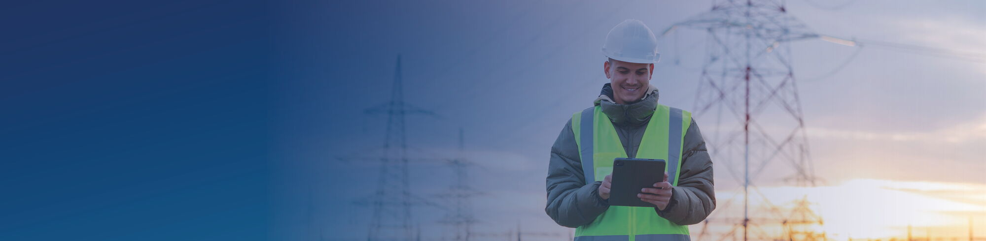 Mitarbeiter eines Energieversorgers mit Tablet vor Strommasten und Hochspannungsleitungen.